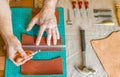 Working process of the leather bag for money or messenger in the leather workshop by master craftsman hands on the table Royalty Free Stock Photo