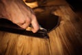 Working process of the leather belt in the leather workshop. Man holding crafting tool and working. Tanner in old