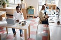 Working in a productive space. a young businesswoman using a headset and laptop in a modern office with her colleagues Royalty Free Stock Photo