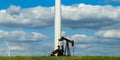 Working pump jack in green field with out of focus grass and flower in front - selective focus Royalty Free Stock Photo