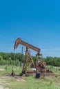 Working pump jack pumping crude oil at oil drilling site in rural USA