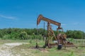 Working pump jack pumping crude oil at oil drilling site in rural USA