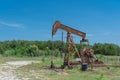 Working pump jack pumping crude oil at oil drilling site in rural USA Royalty Free Stock Photo