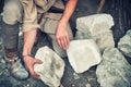 Working in a quarry holding stones. The Mason chooses a white limestone stone for production Royalty Free Stock Photo