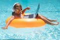 Working and relax on the beach. Child working on laptop computer at poolside swimming pool. Summer online technology. Royalty Free Stock Photo