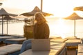 Working remotely on seashore. Young successful woman female freelancer in straw hat working on laptop while sitting on