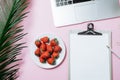 Working space: Laptop, palm leaf, coffee and strawberry on a pin