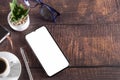 Working table with smartphone notepad coffee cup pen glasses plant on wooden