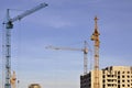 Working tall cranes inside place for with tall buildings under construction against a clear blue sky. Crane and building working Royalty Free Stock Photo