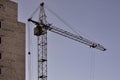 Working tall cranes inside place for with tall buildings under construction against a clear blue sky. Crane and building working Royalty Free Stock Photo