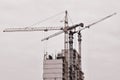 Working tall cranes inside place for with tall buildings under construction against a clear blue sky. Crane and building working Royalty Free Stock Photo