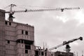 Working tall cranes inside place for with tall buildings under construction against a clear blue sky. Crane and building working Royalty Free Stock Photo