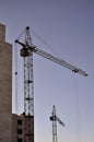 Working tall cranes inside place for with tall buildings under construction against a clear blue sky. Crane and building working Royalty Free Stock Photo