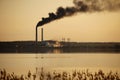 A working thermal power plant on the banks of a river or lake against the backdrop of an evening sunset. Smoking chimneys are a Royalty Free Stock Photo