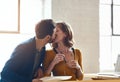 Working together has brought them closer. young couple kissing while working together in their modern office. Royalty Free Stock Photo