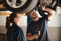 Working together to decide the best course of action. two mechanics working under a car in an auto repair shop. Royalty Free Stock Photo