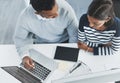 Working together to find better solutions. High angle shot of two young businesspeople going through figures on a laptop