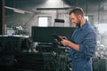 Working by using digital tablet. Man at the factory that is in blue uniform is indoors Royalty Free Stock Photo