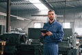 Working by using digital tablet. Man at the factory that is in blue uniform is indoors Royalty Free Stock Photo