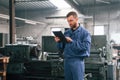 Working by using digital tablet. Man at the factory that is in blue uniform is indoors Royalty Free Stock Photo