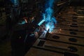 The working welder performs welding work in production using electric arc metal welding