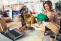 Working women at their store. They accepting new orders online and packing merchandise for customer