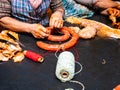 Working women tying red string sausages with rope