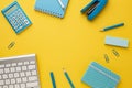 Working yellow table with a keyboard, calculator, notebooks, eraser, pencil, felt-tip pen, stapler and paper clips. Top view with Royalty Free Stock Photo