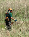 Workman clearing long grass and weeds with Husqvarna tools and safety gear vertical