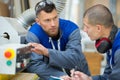 workman explaining how machinery works to new-recruit