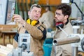 Workman explaining machinery controls to factory apprentice