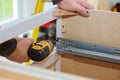 A workman fixing cabinet with screwdriver in kitchen