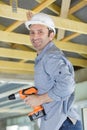 workman fixing roof beam with cordless drill