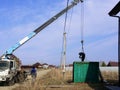 Workman hitchs green cargo container to truck manipulator with gray boom over a power line Royalty Free Stock Photo