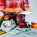 Workman holding nootebook and pen. Price list of repair chainsaw. Small business