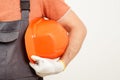 Workman holding orange helmet close up. Worker in a construction site. Builder wearing a protective glove