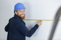 workman holding tape measure against wall