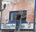 Workman on ladder renovating shop front