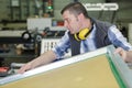 Workman lifting awkward object in factory