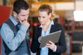 workman looking at tablet with suited woman in workshop Royalty Free Stock Photo