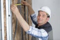 workman measuring wall packed with insulation Royalty Free Stock Photo