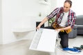 Workman mounting water heating radiator near the window in the white renovated living room, Image with copy space