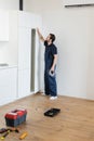 workman opening kitchen cabinet while holding Royalty Free Stock Photo