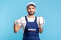 Workman in overalls and gloves pointing mobile phone with mock up blank display, advertising area