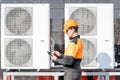Workman servicing air conditioning or heat pump with digital tablet Royalty Free Stock Photo