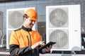 Workman servicing air conditioning or heat pump with digital tablet Royalty Free Stock Photo