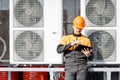 Workman servicing air conditioning or heat pump with digital tablet Royalty Free Stock Photo