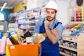 Workman standing folded arms near basket with picked tools in pa