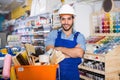 Workman standing folded arms near basket with picked tools in pa