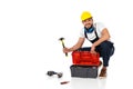 Workman in uniform holding hammer near toolbox and tools on white background